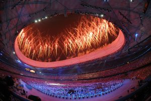 stadium performance with crowd, fireworks blasted into the air from circular building
