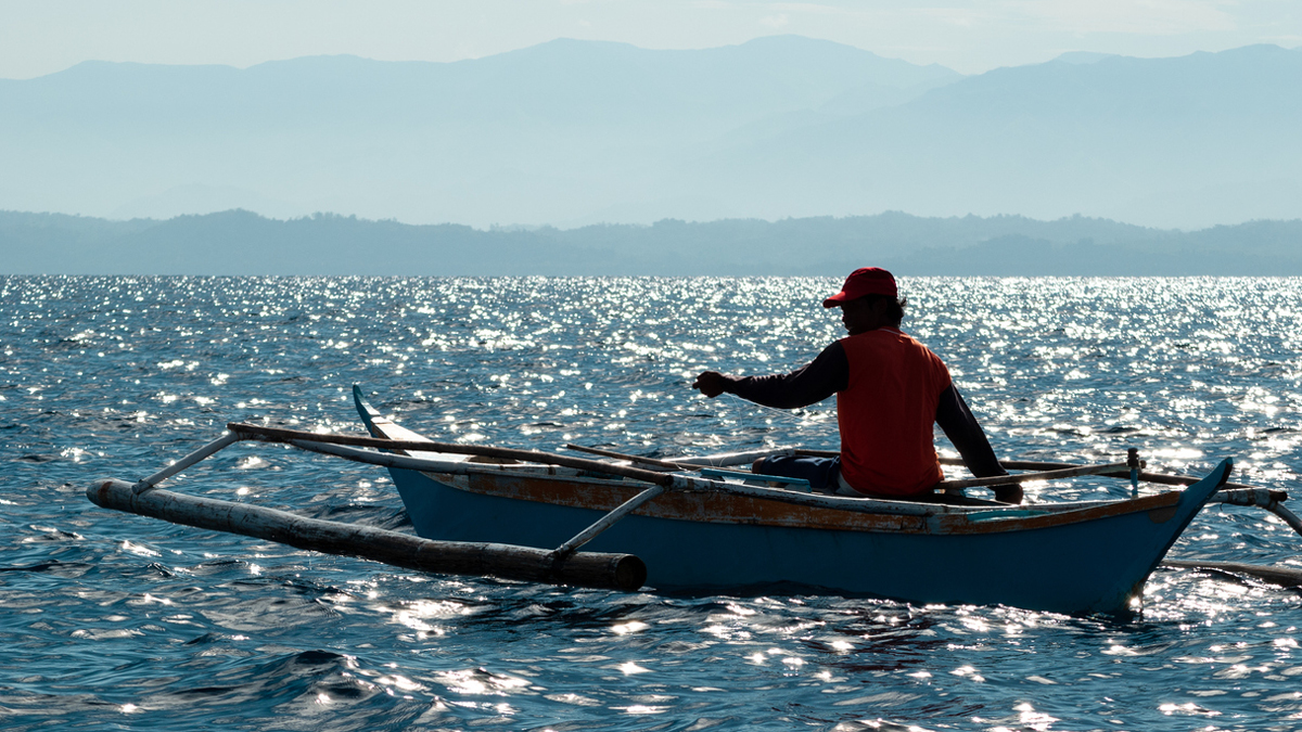 A lone fisherman onboard a small outrigger fishing boat. Sablayan, Mindoro Occidental, Philippines
