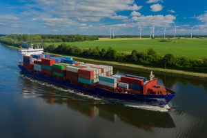 Container ship on the Kiel Canal and windmill on the background