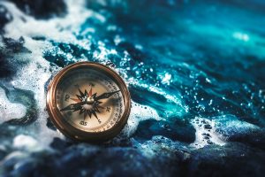 Compass on rocks with sea water