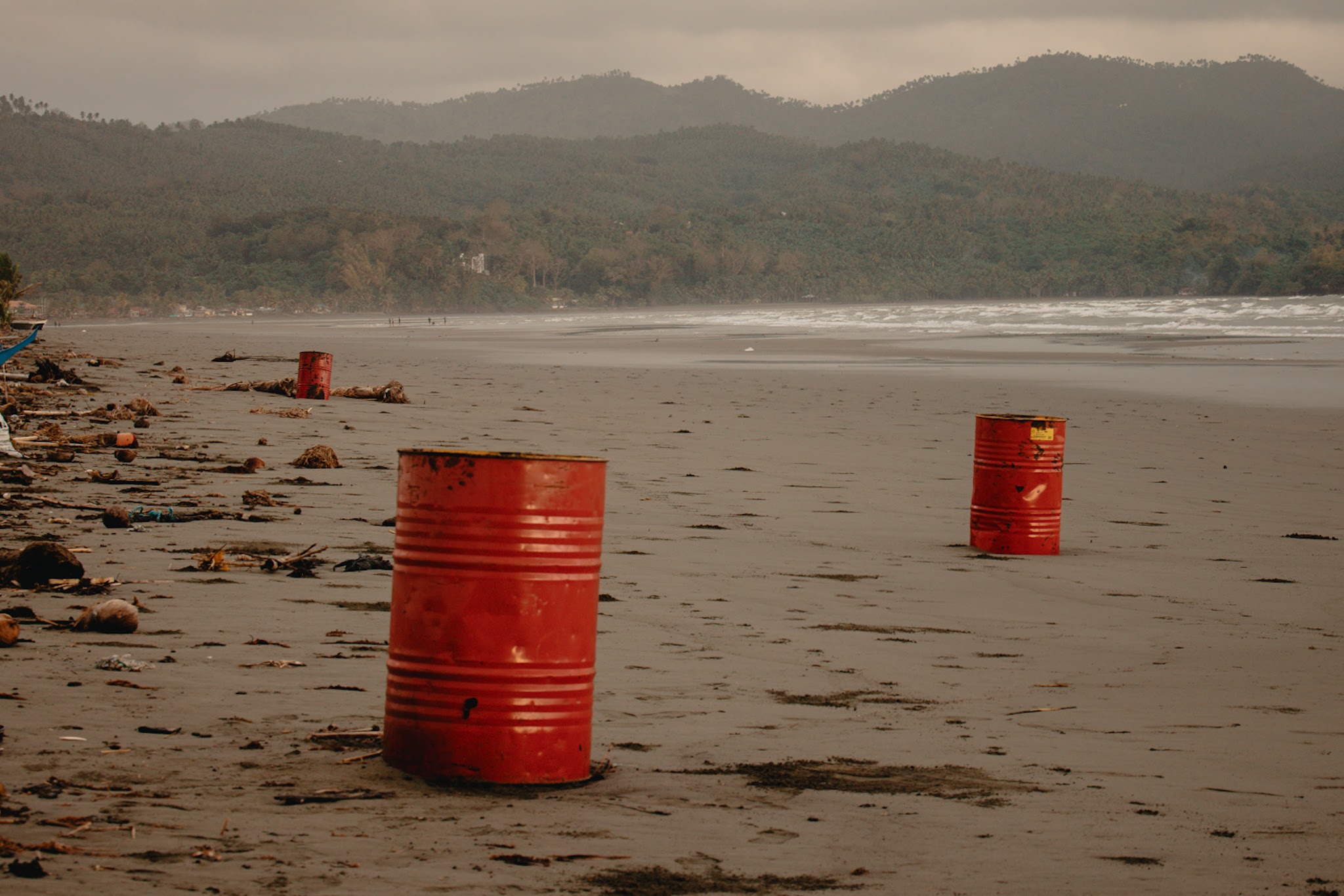 Red drums containing oil from the clean-up drive dot the once pristine coasts of Pola.