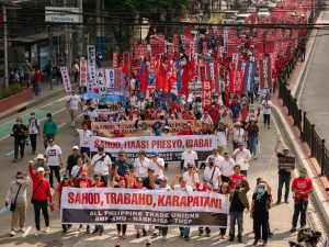 Protestors in Philippines marching on the street with banners amplifying "SAHOD, TRABAHO, KARAPATAN".